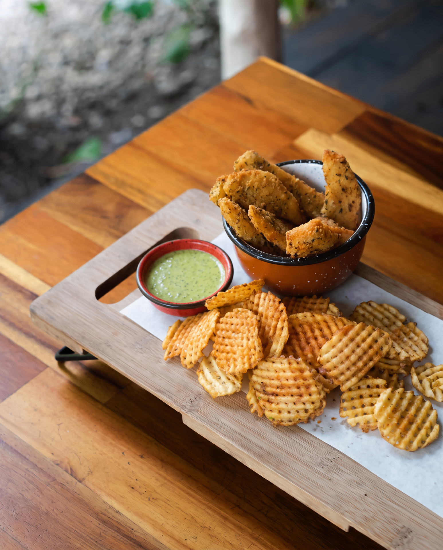 Bastones de pollo crujientes con papas mallita y salsa verde de la casa.