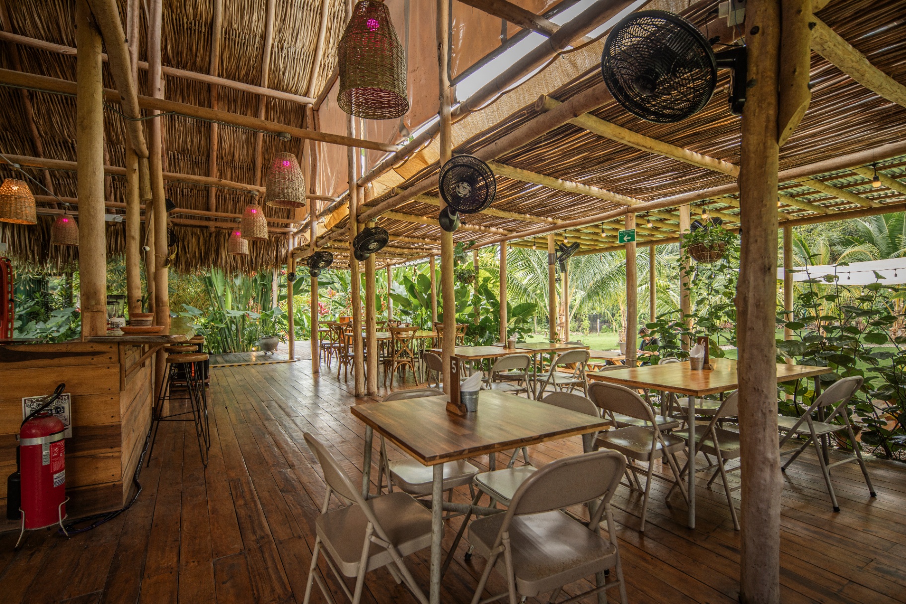 Interior del pabellón en bambú y palma con vista al jardín tropical